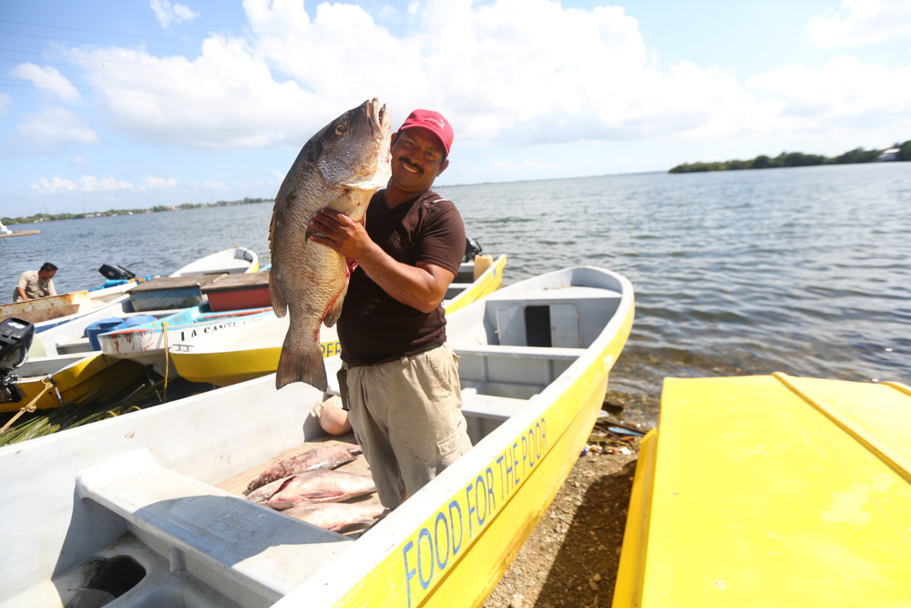 A fisherman in Honduras proudly holds up one of many fish he caught in the Caribbean Sea. Food For The Poor's Fishing Village program supplies destitute coastal villages with fiberglass boats with outboard engines, global positioning systems, fishing tackle, 100-quart coolers, safety equipment, a gear shed with a freezer, a generator and a powerful solar-powered street light for the village common area, as well as training in deep-sea fishing. There are 15 fishing villages in Jamaica, 39 in Haiti, 15 in Honduras and one in Dominica. (Photo by Food For The Poor)